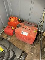 Group of red fuel cans showing quantities and condition