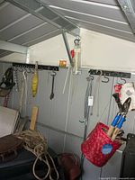 Overall view of back wall with hanging garden tools, tote and watering can