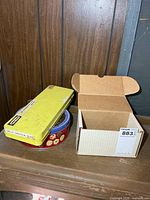 Full lot showing yellow cleaning kit tin, round grease tin and cardboard box