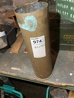 Full view of brass shell casing standing upright with size label