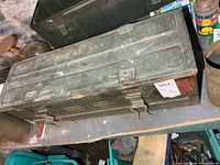 Top and side view of green steel military case with stencilled text