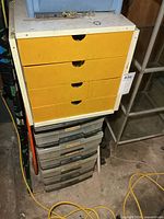 Upper white melamine cabinet with yellow drawers stacked on plastic drawer tower