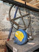 Blue Power Fist drum plumbing snake and metal fish tape reel against wall