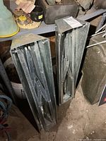 Two folded galvanized steel sawhorses standing upright on floor