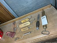 Group shot of knife, five pocket scales, axe head and sheaths on shelf
