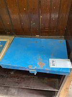 Closed blue metal case with latch, rust spots visible