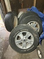 Stack of four tires on rims showing overall lot