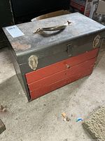 Front view showing lid, handle, two latches, drawers closed