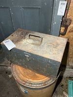 Closed metal toolbox showing exterior wear and handle