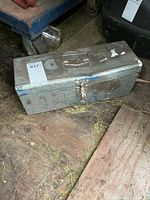Closed gray metal toolbox with latch, exterior wear visible