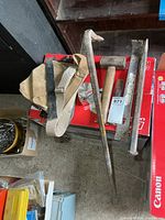 Lot overview showing wrecking bar, flat bars, chisels, sledge, tool belt