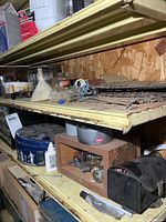 Two shelves showing assorted hardware, organizer, tins, multimeter case