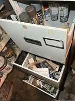 Three open drawers with paints and hardware visible