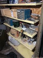 Four lower shelves containing hardware cabinet, wood box, wire spool, bags of mix