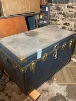 Full view of blue composite trunk with brass-tone hardware