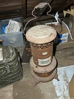 Full view of rusted Gurney Oxford oil heater showing overall form and handle