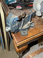 Side view of blue cast iron bench vise on table
