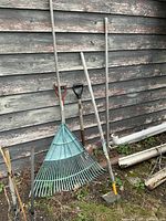 Group of long-handled garden tools leaning against wall