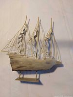 Full view of metal ship sculpture showing three masts, sails, hull and base