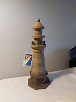 Full view of wooden lighthouse on white surface
