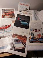 Overview of six loose magazine ad pages spread on surface
