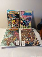 All four comics laid out: Crisis on Infinite Earths, The Transformers, two Wolverine: First Class