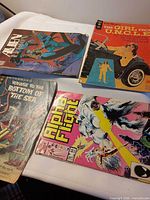Top view of four comic books: Alien, The Girl from U.N.C.L.E., Voyage to the Bottom of the Sea, Alpha Flight