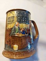Front view showing relief scene, handle, glaze colours, year visible on base rim
