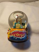 Front view of snow globe showing Las Vegas banner and clown on base