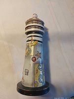 Front view of wooden lighthouse showing painted shell, starfish and wave motifs