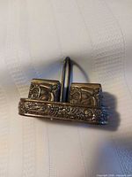 Front view of silver-plated square shakers seated in floral-relief caddy
