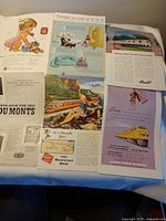 Sheet displaying multiple clipped 1950s ads laid out on table