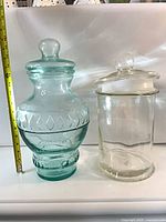 Aqua and clear glass jars side by side with tape measure for scale