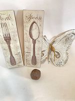 Metal butterfly, two utensil plaques and bird figurine grouped