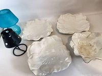 Group view of three flower plates, flower bowl, black metal tealight holder, blue glass votive