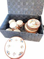 Open basket showing cups, saucers and stacked plates