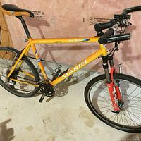 Full side view of yellow-orange Marin mountain bike showing frame, fork, drivetrain and missing pedals