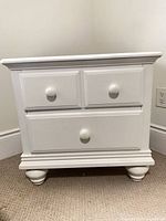 Front view showing full nightstand, drawer fronts, bun feet