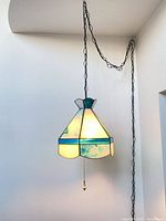 Full view of stained glass pendant lamp hanging from ceiling with chain and cord