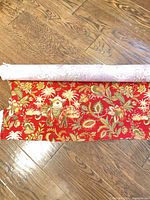 Red botanical elephant print fabric roll on hardwood floor