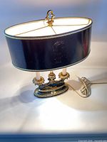 Full view of lit bouillotte lamp showing shade, base and cord