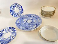 Group view of blue transferware plates, stacked gold-rim bowls and handled dish