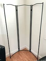 Full view of black metal 3-panel frame standing in corner