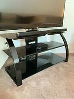 Front view of Bello black TV stand holding TV and soundbar
