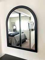 Front view of black arched wall mirror mounted on wall