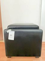 Front view of black faux leather cube ottoman with lid in place