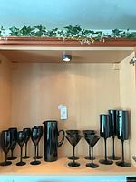 Full set of black glass stemware and pitcher on cabinet shelf