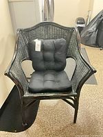 Front view of entire black wicker rattan armchair with cushion
