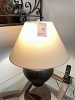 Lamp with shade illuminated on glass table