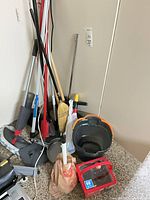 Group of cleaning tools, buckets, broom, mop, dustpan, hose case visible